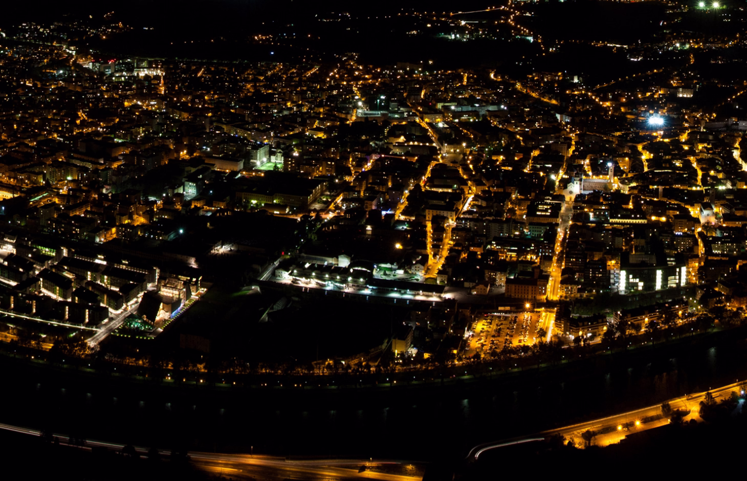 Aerial view of a city at night with illuminated streets and buildings, showcasing urban infrastructure