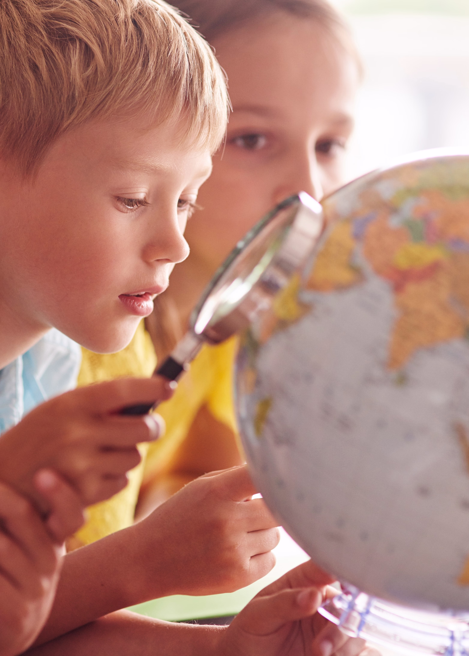 Curious child exploring the globe with magnifying glass during cognitive learning activity